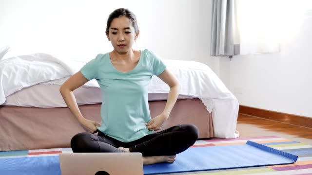 Frau-versucht,-Yoga-Unterricht-aus-dem-Internet-im-Schlafzimmer-zu-lernen.