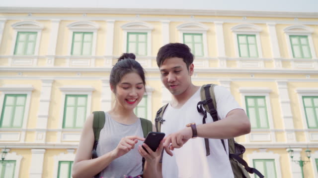 Viajero-asiático-dirección-de-pareja-en-el-mapa-de-ubicación-en-Bangkok,-Tailandia,-la-pareja-usando-el-teléfono-móvil-mirando-en-el-mapa-encontrar-un-hito-durante-el-viaje-de-vacaciones.-Viaje-pareja-de-estilo-de-vida-en-concepto-de-ciudad.