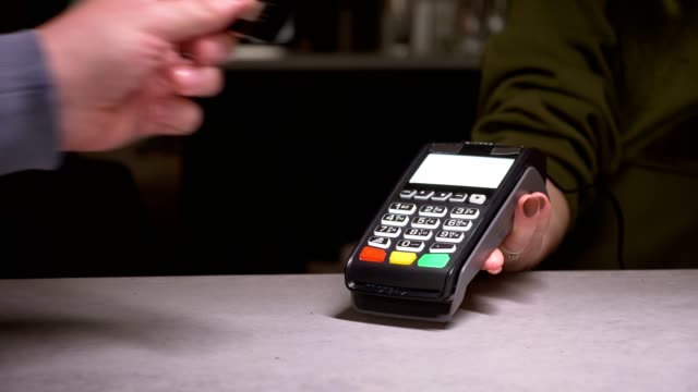 Close-up-shot-of-person-using-terminal-and-credit-card-performing-contactless-payment.