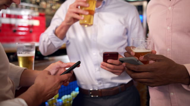 Gruppe-von-Geschäftsleuten-alle-Überprüfen-Handys-während-Treffen-für-Trinken-in-Bar
