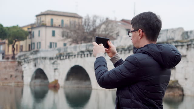 Mann-fotografiert-mit-Smartphone-Brücke