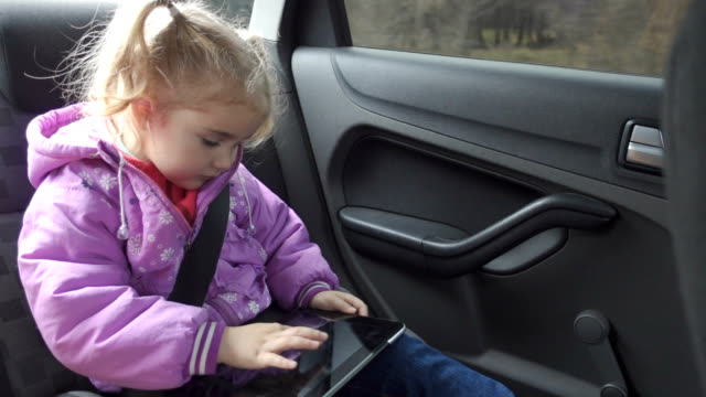 Kleines-Mädchen-warme-Kleidung,-spielen-auf-Ihrem-Tablet-PC-im-Auto
