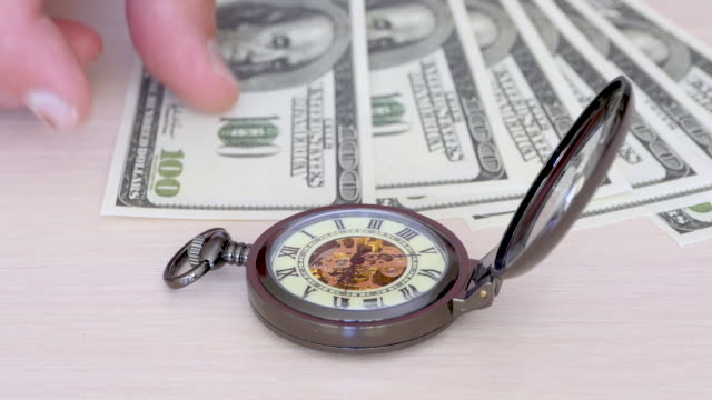 Zeit-ist-Geld---eine-Taschenuhr-auf-einem-Hintergrund-von-hundert-Dollar-Scheinen