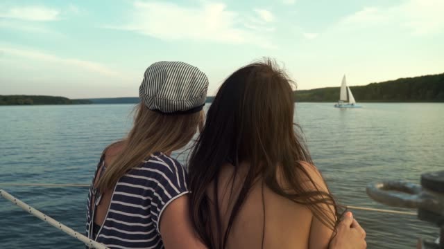 Rückansicht-von-zwei-Lesben,-die-sich-umarmen-und-die-Reise-auf-dem-Segelboot-genießen