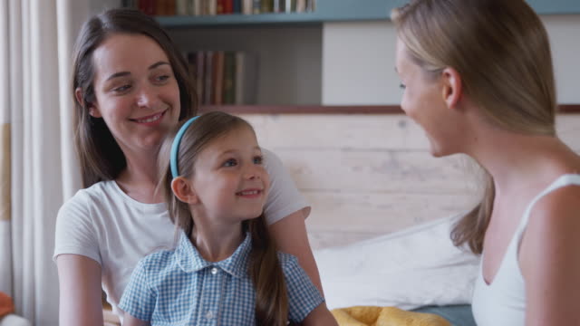 Same-Sex-Female-Couple-At-Home-In-Bedroom-Getting-Daughter-Ready-For-Schoolæ