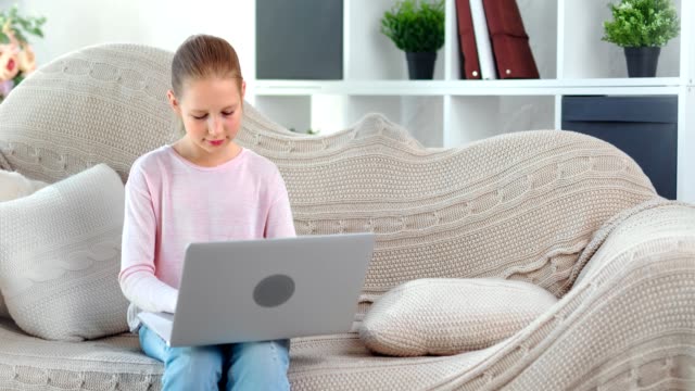 Focused-beautiful-child-girl-chatting-in-social-network-typing-message-using-laptop-pc-medium-shot
