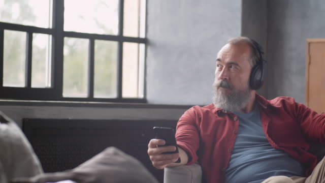 Grey-haired-Bearded-Man-Enjoying-Music-at-Home