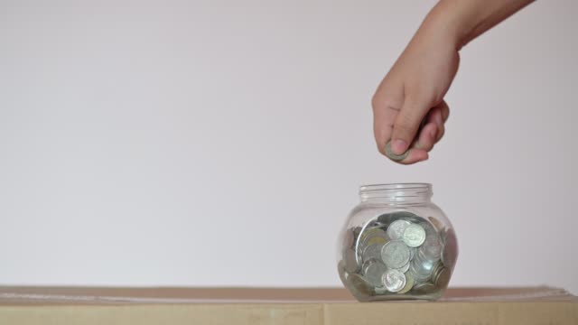 Geschäftsmann-steckt-eine-Münze-in-einem-Glasflaschen-Konzept,-Geld-zu-sparen-und-in-Finanzgeschäfte-zu-investieren.-Video-4K