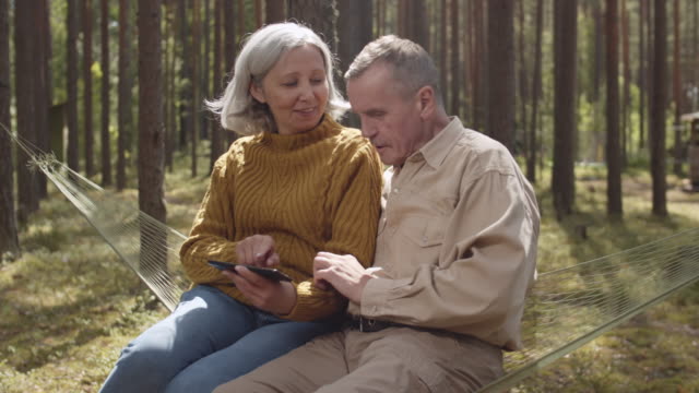 Senior-Couple-Sitting-in-Hammock-in-Woods