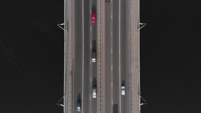 Puente-carretera-de-agua-oscura-coche-rojo-en-el-tráfico-aéreo-vista-superior
