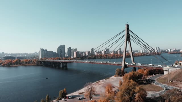 Gran-puente-de-hormigón-con-remolques-de-cuerda-de-acero-que-conecta-dos-orillas-de-la-gran-metrópolis.-Vista-aérea-de-drones-del-puente-con-tráfico-de-coches-concurrido,-Kiev,-Ucrania