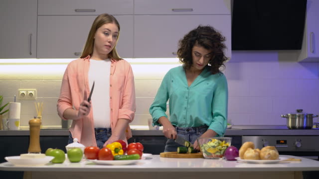 Jóvenes-mujeres-bonitas-hablando-en-la-cocina,-preparando-comida-vegetal,-comunicación