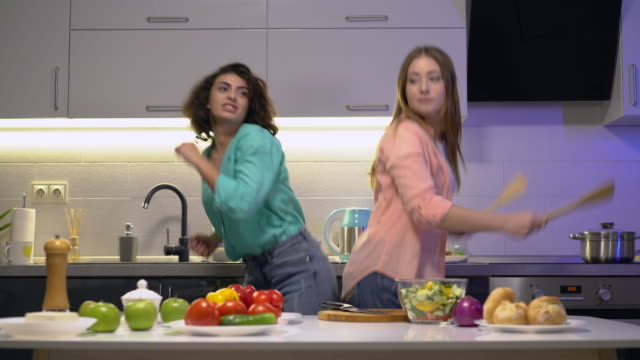 Happy-young-women-enjoying-cooking,-dancing-in-home-kitchen-together,-leisure