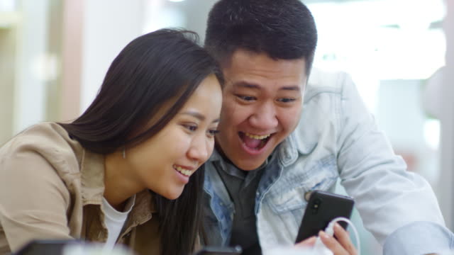 Pareja-asiática-probando-Smartphone-en-la-tienda