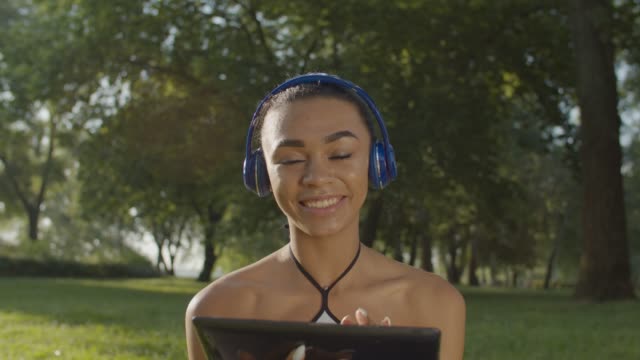 Hübsche-Frau-in-Kopfhörern-genießen-Musik-im-Park