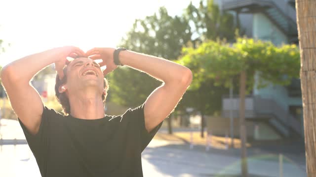 Carefree-young-man-shaking-body-while-enjoying-music-in-city-on-sunny-day.-High-quality-4k-footage