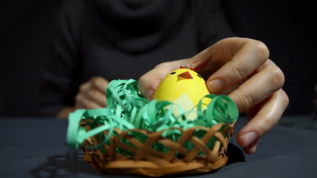 Creating-easter-souvenir-from-chicks-of-eggshells-by-hand-on-a-grey-table.