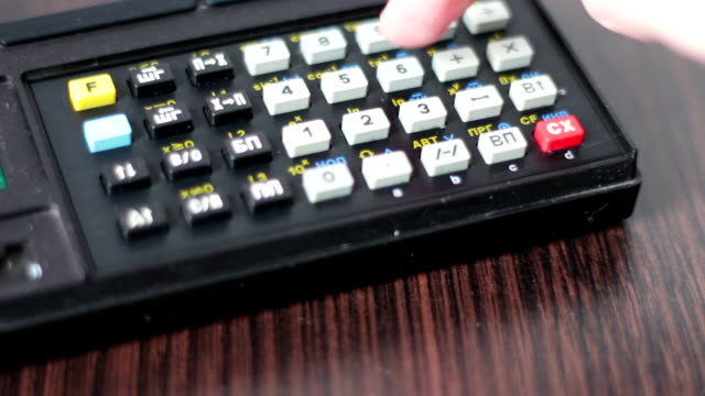 Hand-operates-old-retro-calculator-at-workstation