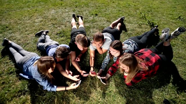 Top-view-teenagers-in-circle-using-phones-in-park