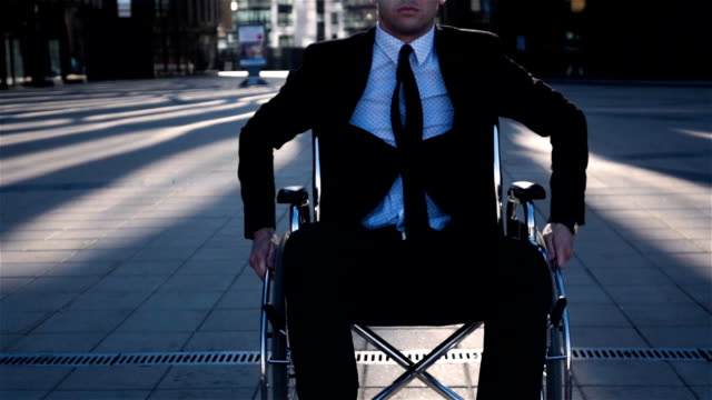 Krüppel-Geschäftsmann-bewegen-im-Rollstuhl-vor-der-Kamera-im-Freien-in-der-Nähe-von-Business-Center