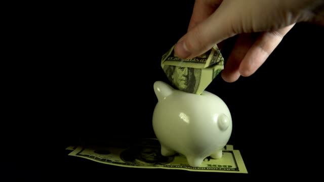 Sparschwein-und-Dollarnoten-drehen-auf-einem-schwarzen-Hintergrund