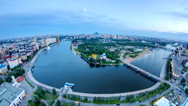 Elevated-view-over-the-city-center-with-river-and-park-and-central-business-district-day-to-night-Timelapse,-Central-Asia,-Kazakhstan,-Astana