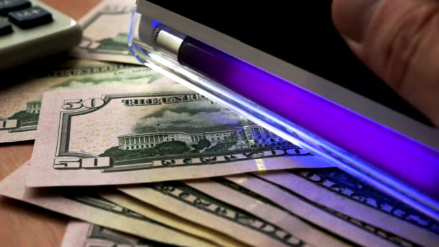 Checking-bills-with-uv-light.-Dollars-under-ultraviolet.
