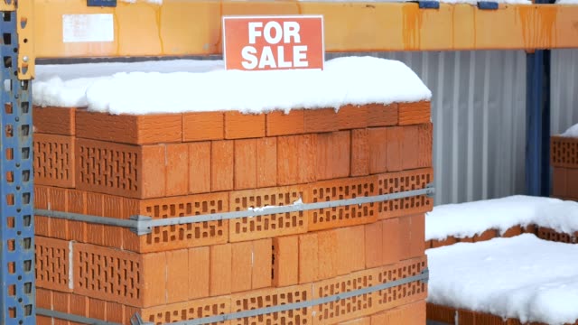 Stack-of-orange-clay-brick-with-snow-"For-sale"-words
