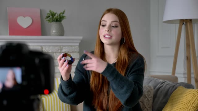 Young-red-haired-girl-blogger,-smiling,-talking-at-the-camera,-showing-a-new-purchase,-cosmetics,-Eyeshadow-Pallet,-home-comfort-in-the-background.-60-fps