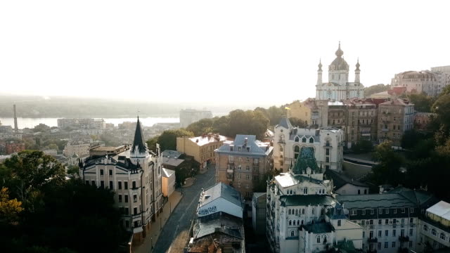 Kiev-Ukraine-aeriel-drone-view-to-Andriyivskyy-Descent,-Podil,-St.Andrew's-Church,-river-Dnepr.-Beautiful-sunrise