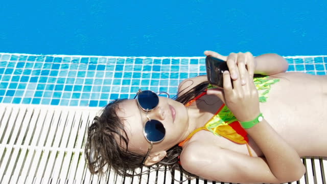 A-child-by-the-pool-with-a-phone.