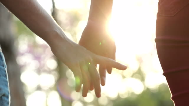 Close-up-of-hands-joining-together-with-sunlight-flare-in-the-background