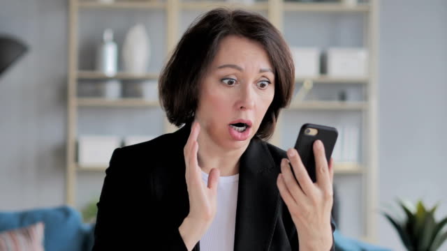 Old-Businesswoman-in-Shock-while-Using-Smartphone