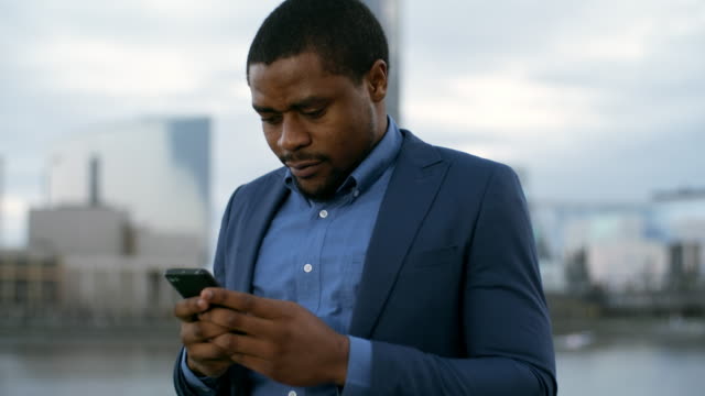 Empresario-africano-chateando-en-el-celular-de-noche