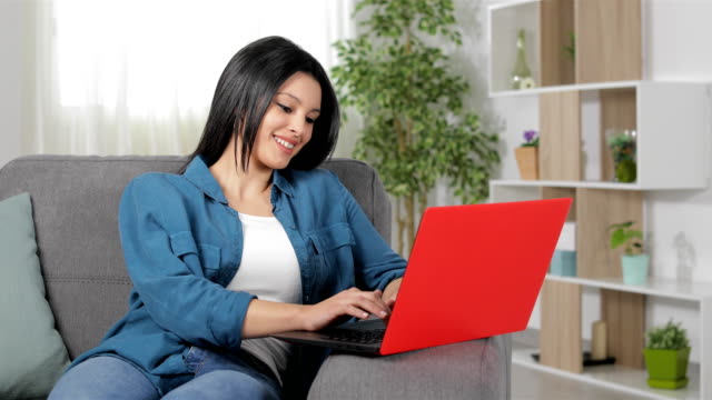Glückliche-Frau-Tippen-auf-Laptop-zu-Hause