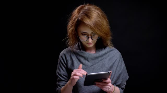 Closeup-portrait-of-attractive-adult-woman-browsing-internet-on-the-tablet-casually-then-looking-at-cameraman-and-smiling