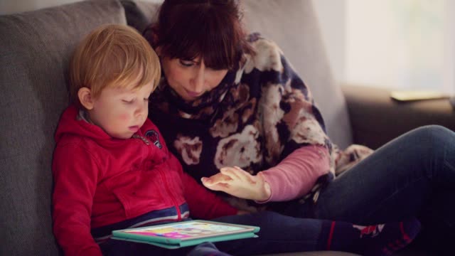 mother-with-her-son-using-tablet-on-sofa-at-home