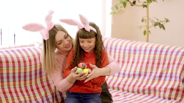 mother-looking-at-daughter-holding-her-hands-which-are-Easter-eggs.