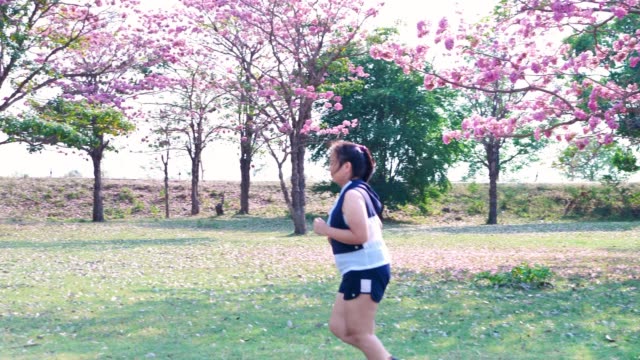 Una-mujer-asiática-gorda-que-trota-en-la-luz-del-sol-natural-por-la-mañana.
Ella-está-tratando-de-perder-peso-con-el-ejercicio.--concepto-de-salud-con-ejercicio.-Cámara-lenta