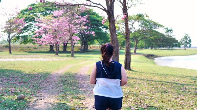 Eine-fette-asiatische-Frau,-die-morgens-im-natürlichen-Sonnenlicht-joggt.
Sie-versucht,-mit-Übung-Gewicht-zu-verlieren.--Konzept-Gesundheit-mit-Bewegung.-Zeitlupe