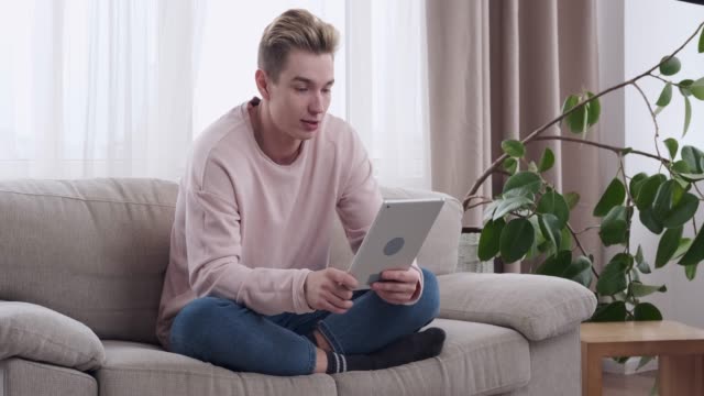 Entspannte-Mann-Videokonferenzen-auf-digitalem-Tablet-zu-Hause