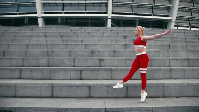 Gemischte-Rasse-blond-lächelnde-Frau-mit-roter-Sportbekleidung-macht-Gymnastik