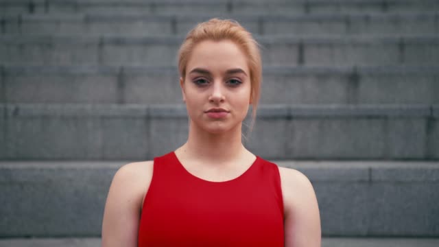 Portrait-of-plus-size-mixed-race-blond-smiling-woman-wearing-red-sportswear-looking-at-camera