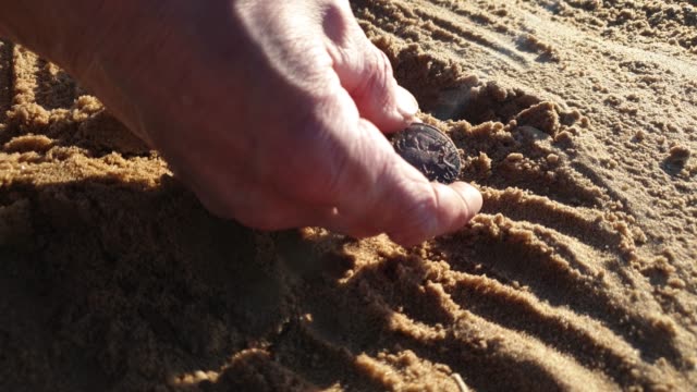 Man-is-looking-for-coins-in-the-sand.-Search-for-antique-coins.