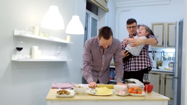 Familia-gay-con-hija-niño-cocinar-pizza-juntos-en-la-cocina-y-abrazando.