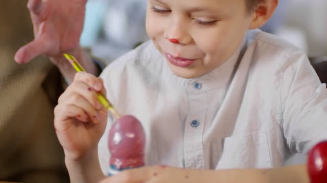 Niño-lindo-decorar-huevos-con-pintura