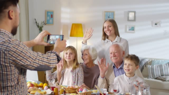 Family-Waving-Hands-and-Smiling-for-Photograph