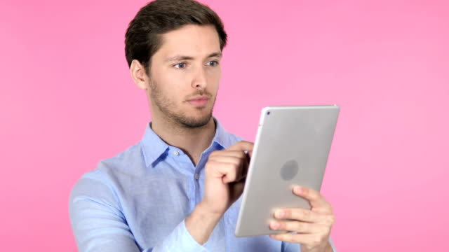 Junger-Mann-nutzt-Tablet-auf-rosafarbenem-Hintergrund