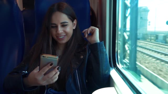 Porträt-des-attraktiven-lächelnden-Mädchen-im-Zug-mit-Smartphone-im-Chat-mit-Freunden-Frau-Hand-Internet-Technologie-Mobilfunk-Stadt-Smartphone-Smartphone-Trasse-Transport-jung