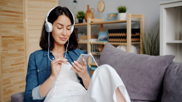 Schöne-junge-Frau-hört-Musik-über-Kopfhörer-per-Smartphone